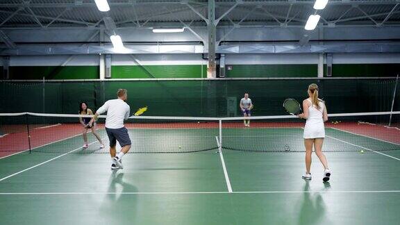 一群朋友在操场上打网球成年的男男女女在操场的不同方向扔网球
