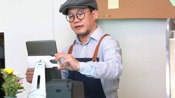 4K亚洲人咖啡店老板正在检查数码平板电脑的库存