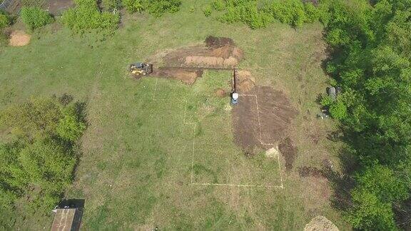 挖掘机在绿色的田野上挖土的天线上面标记着未来的房子