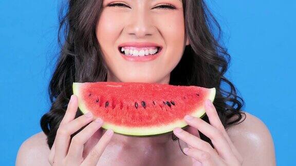 肖像快乐的年轻女子微笑着拿着一片西瓜在彩色的蓝色背景夏天