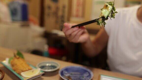 年轻女子在日本居酒屋酒吧吃东西