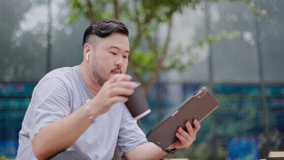 亚洲男性商人独自远程工作时戴着在线会议耳机和平板电脑写在平板电脑上工作以外的