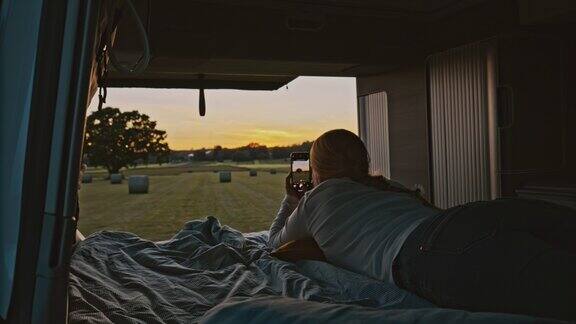 一个叫DL的女人用她的手机拍下了日落时分停在草地上的露营车的小屋里的照片
