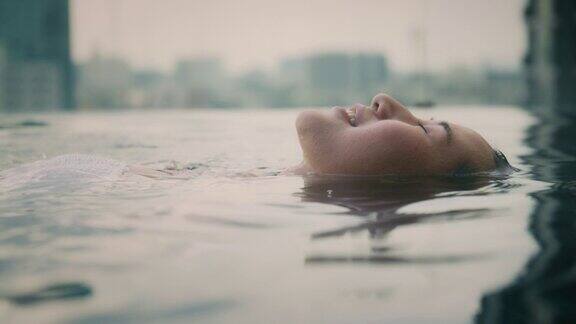 迷人的年轻亚洲女子漂浮在游泳池的水面上