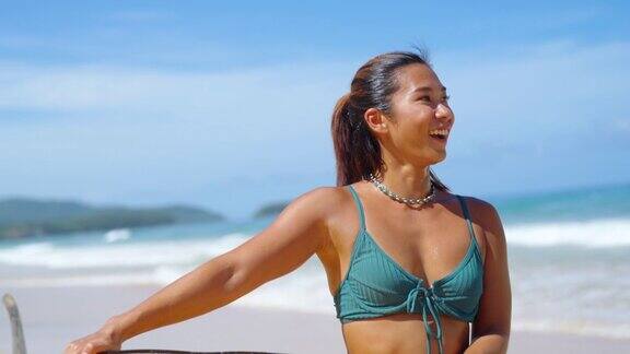 4K亚洲妇女拿着冲浪板走到海洋在夏天阳光明媚的一天
