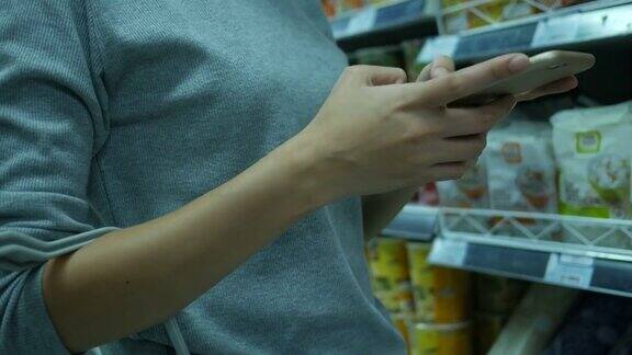 在超市用智能手机的女人