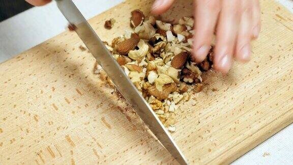 厨师用手在木砧板上切坚果