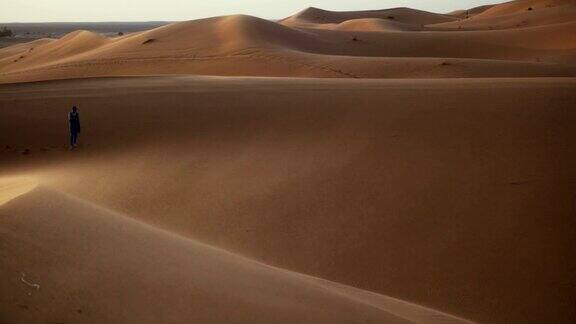 日落时分撒哈拉沙漠中行走的女子