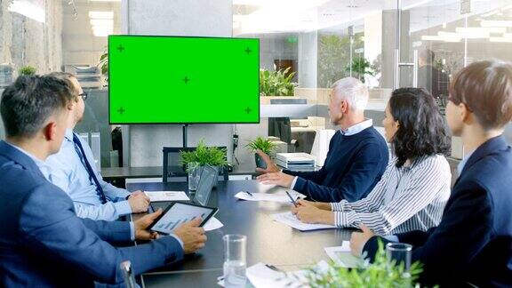 各种各样的成功商业人士在会议室绿屏彩色钥匙电视在墙上他们关注公司的成长分享图表和统计数据