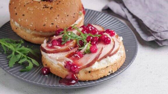 感恩节食品白面包圈三明治配火鸡和灰色盘子里的蔓越莓酱