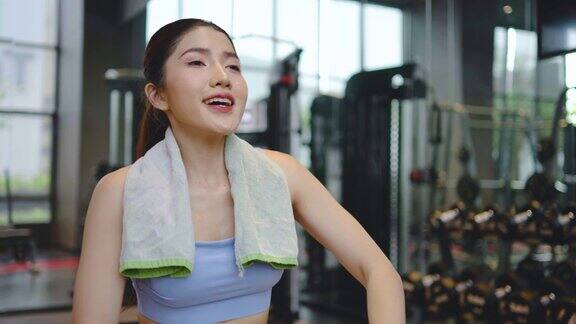 疲惫的亚洲妇女的肖像在运动服饮用瓶装水在健身房女运动员补充水平衡后健身锻炼练习或训练后口渴