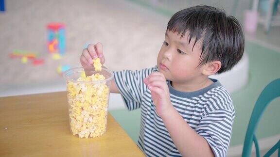 一个小男孩在操场上玩完后正在吃爆米花和米饭