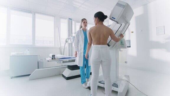 在医院乳房x光技师医生调整乳房x光机为一名女性患者友善的医生讲解预防乳腺癌筛查的重要性现代技术先进的诊所与专业医生