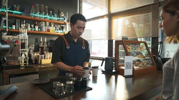 4K亚洲男子咖啡师在吧台为顾客准备外卖点的热咖啡