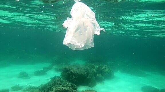 塑料袋漂浮在水下脆弱的珊瑚礁上