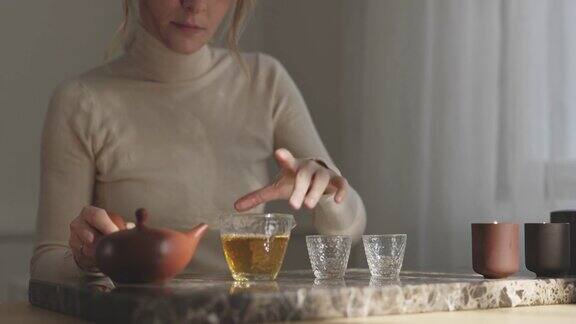 泡茶:一个美丽年轻女子的手把茶倒进小杯子里