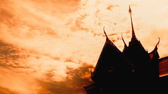 泰国寺庙的剪影在移动的云和橙色的天空
