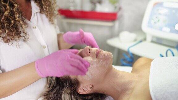 美容师在女性客户脸上按摩润肤霜