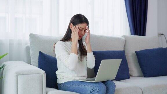 办公室综合症劳累过度的年轻亚洲女性在电脑工作后感到头痛和视力问题紧张的年轻女子在家里饱受疲劳之苦