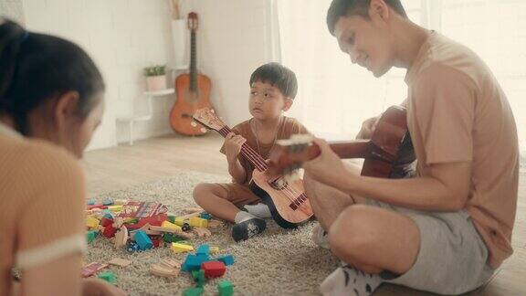 快乐的亚洲父子通过音乐联系在一起在家里一起弹吉他
