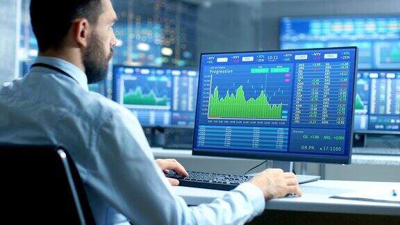 股票市场交易员在显示股票行情数字和图表的计算机上工作的肩部视图