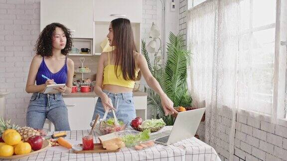 4k视频两个十几岁的姐妹在家里的厨房里做蔬菜沙拉家庭度假活动快乐地生活在一起烹饪娱乐生活中很少奢侈