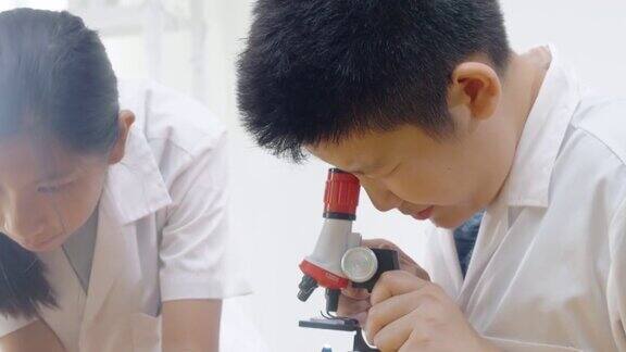 亚洲儿童穿着实验服用显微镜做科学实验在家学校实验室教育生活理念