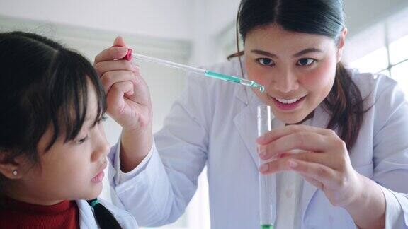 近距离教师教学与小学生化学讲解他们在学校实验室的烧杯中学习科学和化学混合