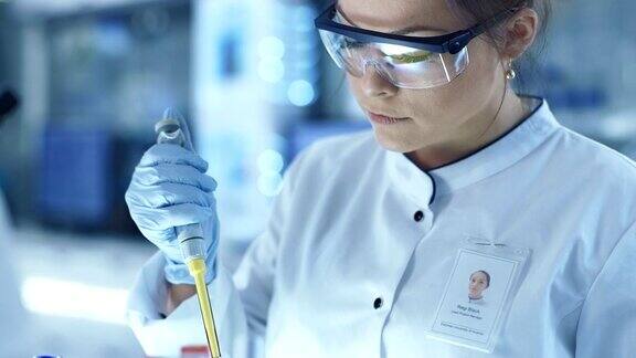 女研究科学家在一个大的现代实验室使用微型管填充试管在背景中科学家正在工作