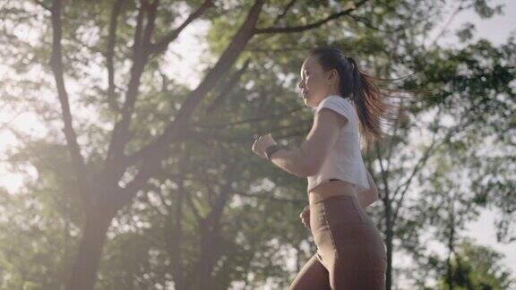 快乐放松的成熟女性慢跑过积极健康的生活方式早上锻炼锻炼快乐微笑的成年亚洲女性在阳光明媚的夏日在城市公园户外慢跑健康积极的生活方式理念