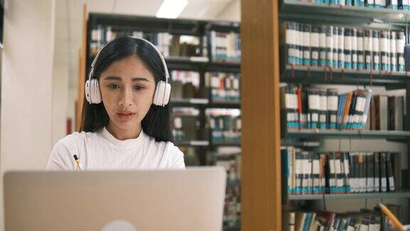 年轻漂亮的亚洲学生在学校图书馆学习并使用笔记本电脑进行在线学习e-Learning教育理念回到学校