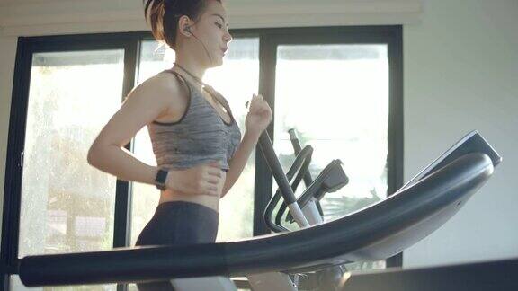 年轻女子在健身房的跑步机上锻炼和慢跑