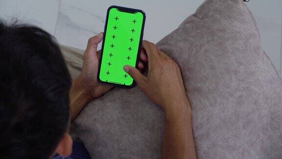 亚洲男性使用绿色屏幕的智能手机