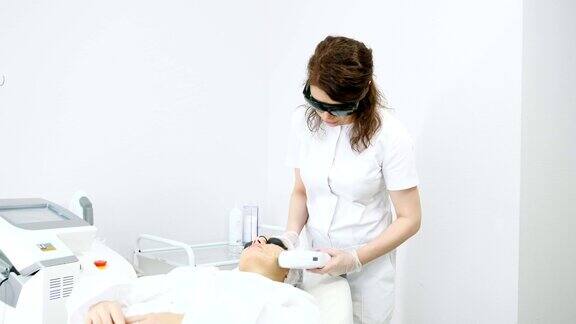 熟练的治疗师在病人脸上做激光脱毛