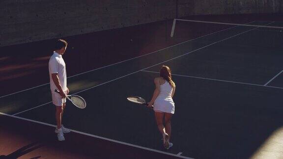 女人和男人在一个阳光明媚的日子里打网球