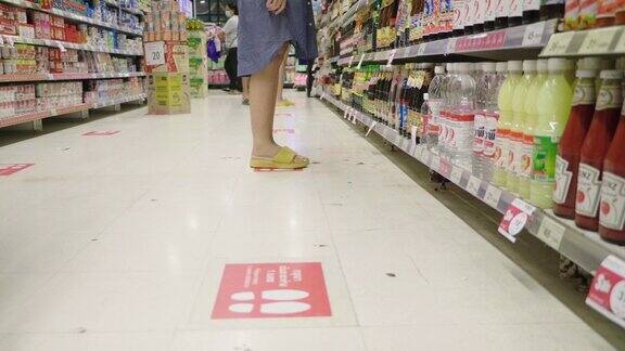 戴着防护口罩的亚洲孕妇和男婴在超市货架上挑选产品