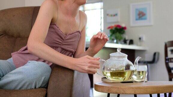 女人在沙发上放松喝着新鲜的茶