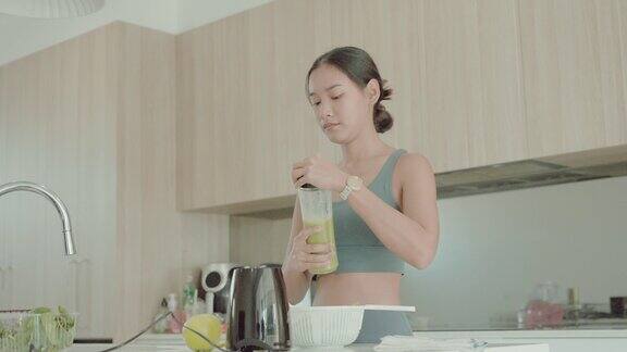 年轻的亚洲妇女在锻炼后享受绿色排毒奶昔健康的生活方式
