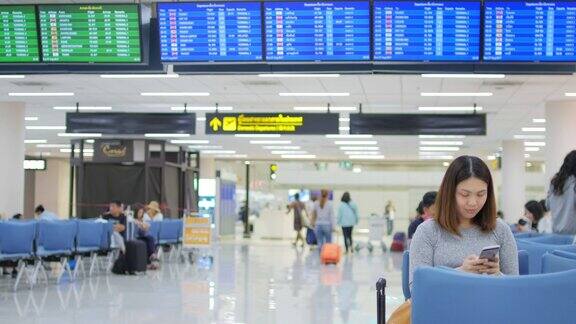 一名女性乘客在机场候机时触摸并使用智能手机