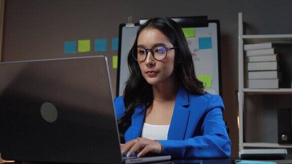 年轻的亚洲女性晚上坐在公司办公室里工作商务女性加班因为工作量大而加班在正常工作时间之外工作加班