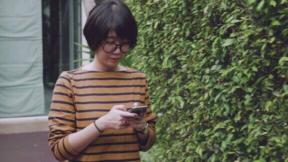 日落时分一名亚洲女子在花园里使用智能手机