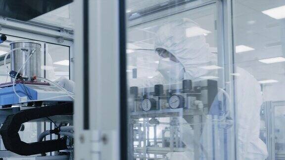 一组科学家穿着无菌防护服在现代工业3D打印机器上工作制药生物技术和半导体创造制造过程从内部拍摄