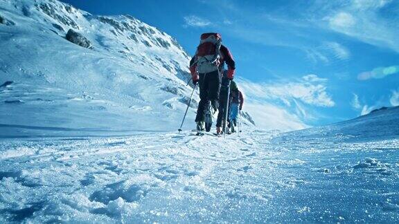 在阳光明媚的日子里滑雪游客攀登上山