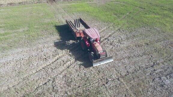 无人机拍摄的一辆拖拉机在干燥的土地上拉着一辆拖车