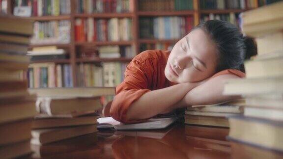 疲倦的亚洲学生睡在一堆书休息学习
