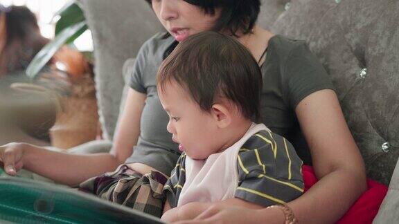 亚洲小男孩和妈妈一起坐在餐厅的沙发上阅读和看菜单食物