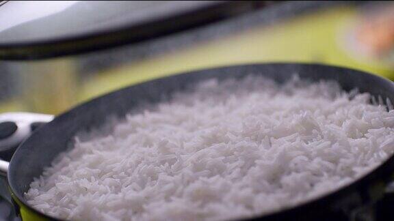 在砂锅炊具中热气腾腾的米饭打开锅盖的白米