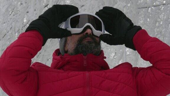 一个成熟的男人在滑雪场雪地上戴上滑雪眼镜的特写肖像赏冬山准备在白雪皑皑的山上滑雪下坡滑雪