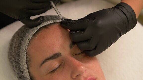 美容诊所美容师双手戴着手套在女性皮肤上注射衰老剂一位妇女接受美容美容手术肉毒杆菌素注射胶原蛋白4k拍摄