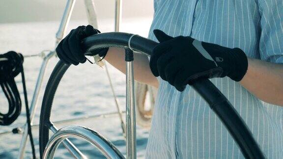 近距离的女性双手在手套处理船的车轮